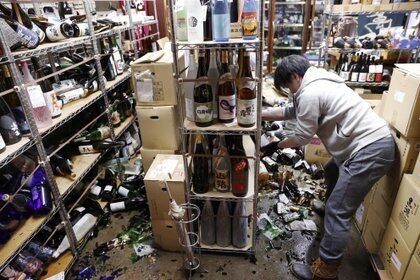 Un trabajador limpia botellas rotas en una licorería después de un fuerte terremoto en Fukushima, Japón, el 13 de febrero de 2021. Crédito obligatorio Kyodo / vía REUTERS