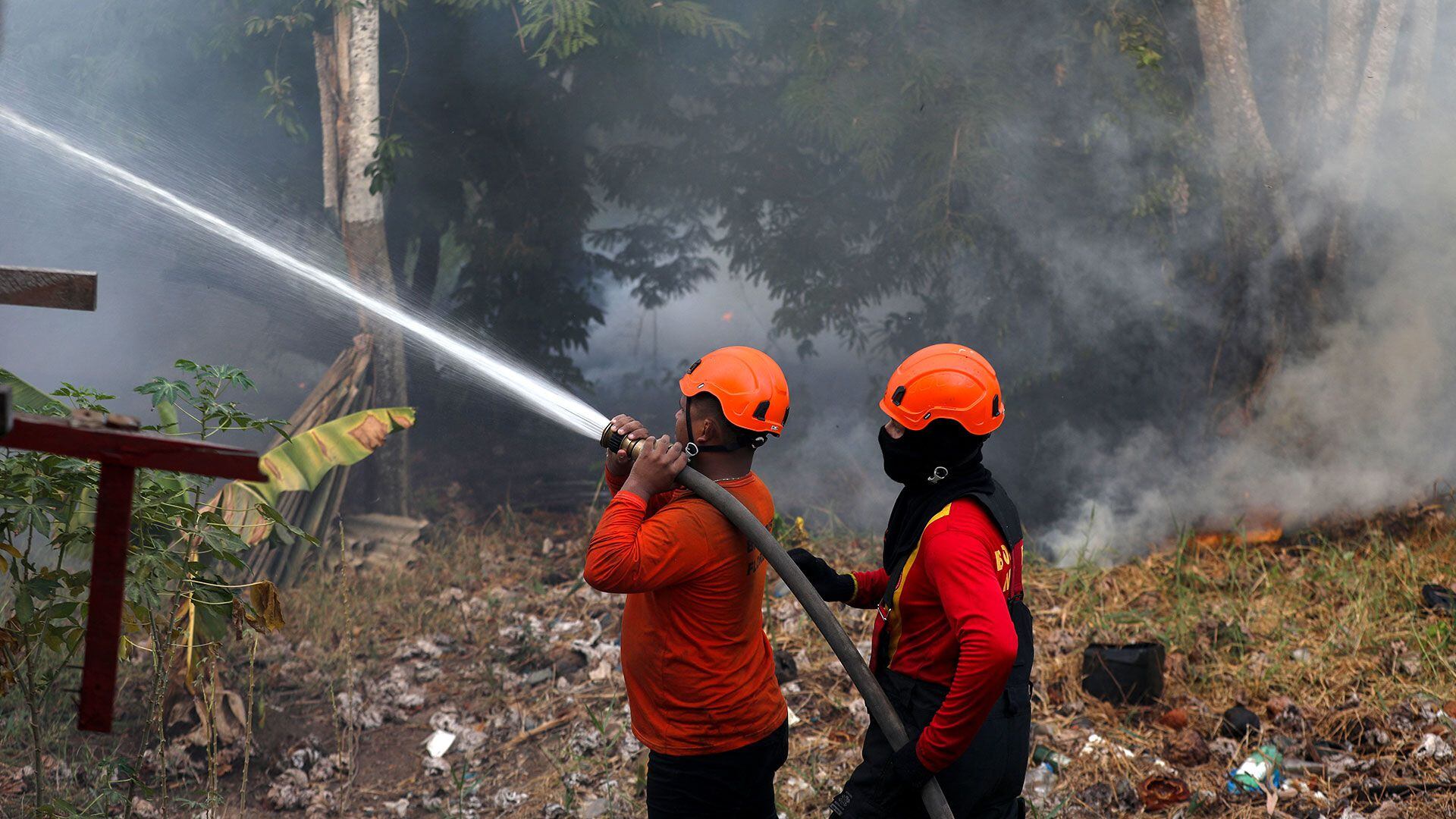 Dos bomberos trabajan para apagar las llamas (Michael Dantas/AFP)