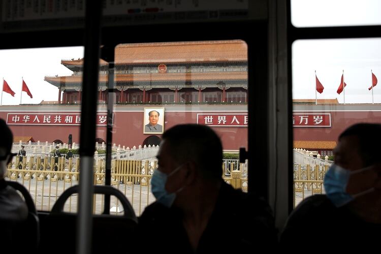 Personas con máscaras faciales en un autobús mientras pasan por la Puerta de Tiananmen en Beijing, China, el 15 de abril de 2020 (Reuters/ Tingshu Wang)