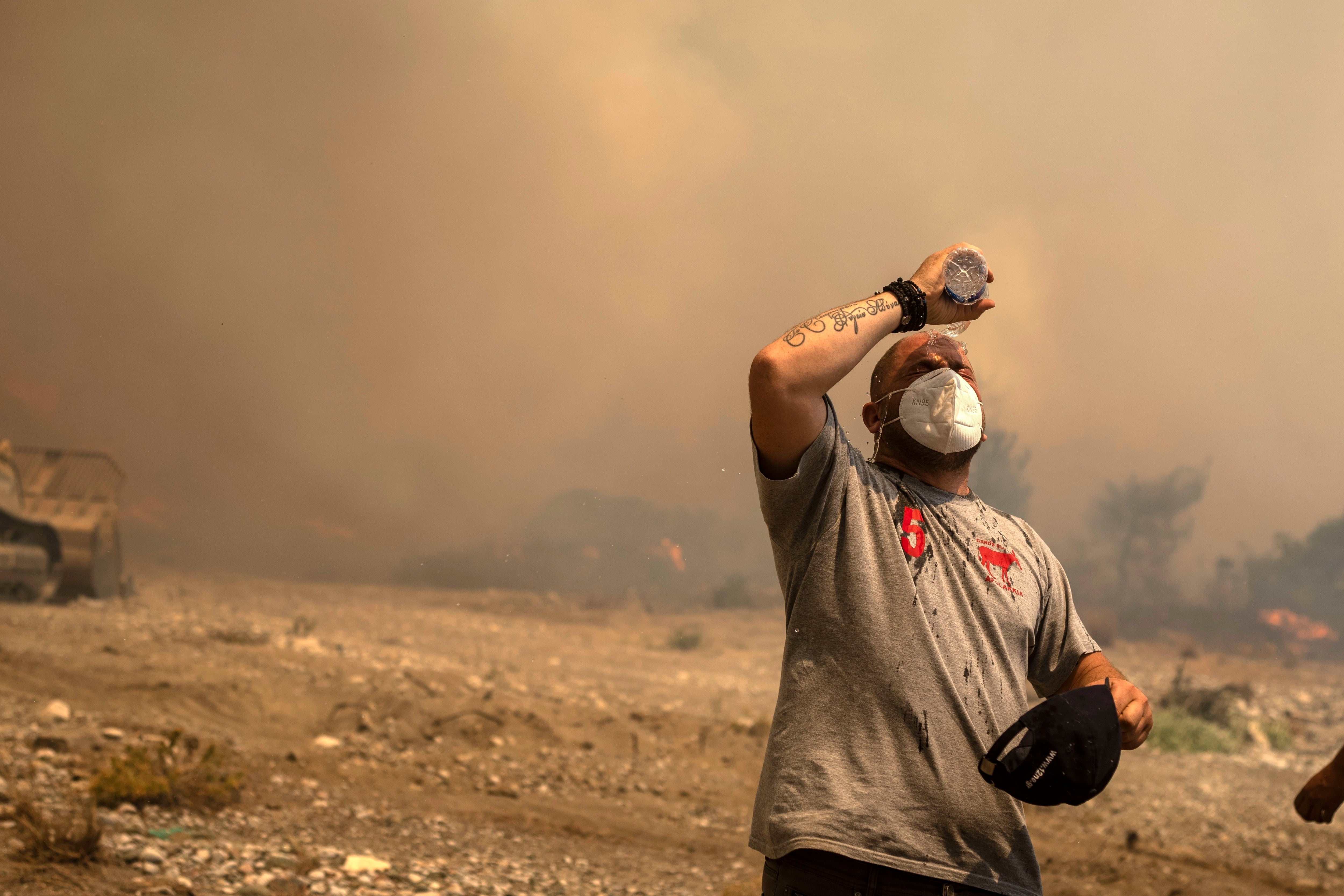 Un voluntario se refresca durante un incendio forestal en la aldea de Vati, en la isla de Rodas, en el mar Egeo, en el sureste de Grecia, el martes 25 de julio de 2023.  (Foto AP/Petros Giannakouris)