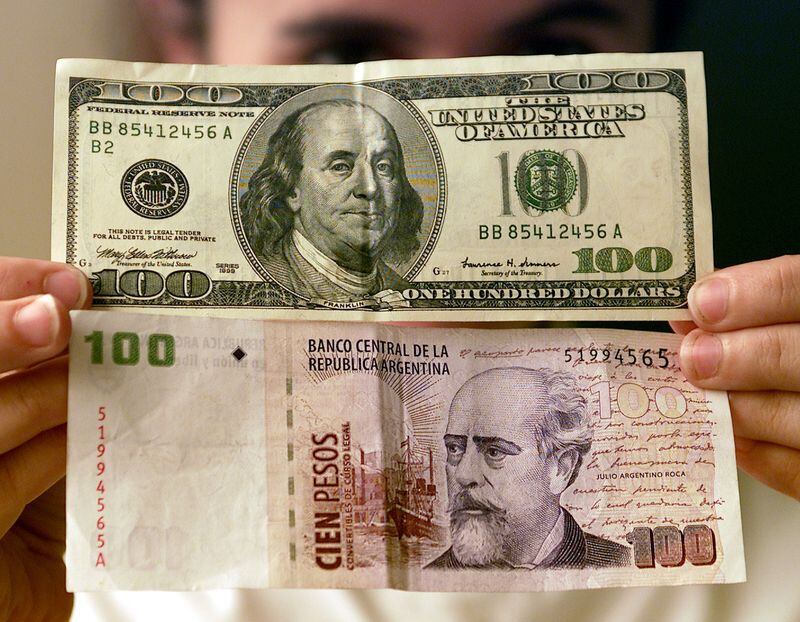 Foto de archivo - Una mujer sostiene un billete de 100 dólares con uno de devaluados 100 pesos argentinos. REUTERS/Enrique Marcarian