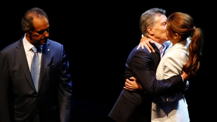 El beso de Juliana Awada a Mauricio Macri, ante la mirada de Daniel Scioli, al terminar el debate presidencial de 2015.