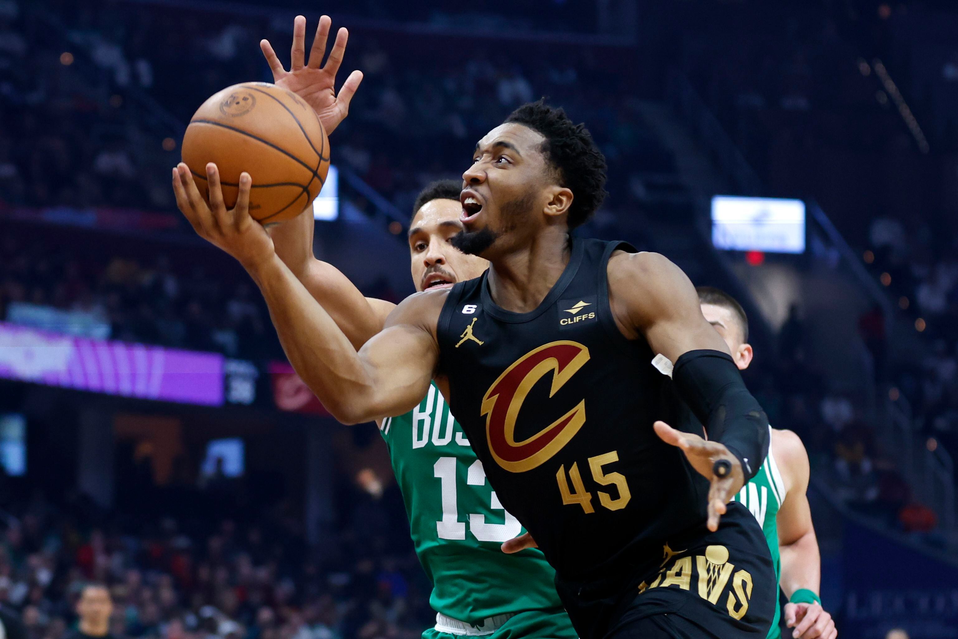 El base de los Cavaliers de Cleveland Donovan Mitchell lanza el balón mientras supera al base de los Celtics de Boston Malcolm Brogdon en el encuentro del lunes 6 de marzo del 2023. (AP Foto/Ron Schwane)