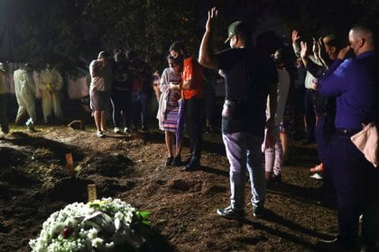 Familiares de una mujer de 77 años que murió por COVID-19 rezan durante su funeral durante la noche en el cementerio de Vila Formosa, en Sao Paulo, Brasil, Marzo 30, 2021. REUTERS/Amanda Perobelli