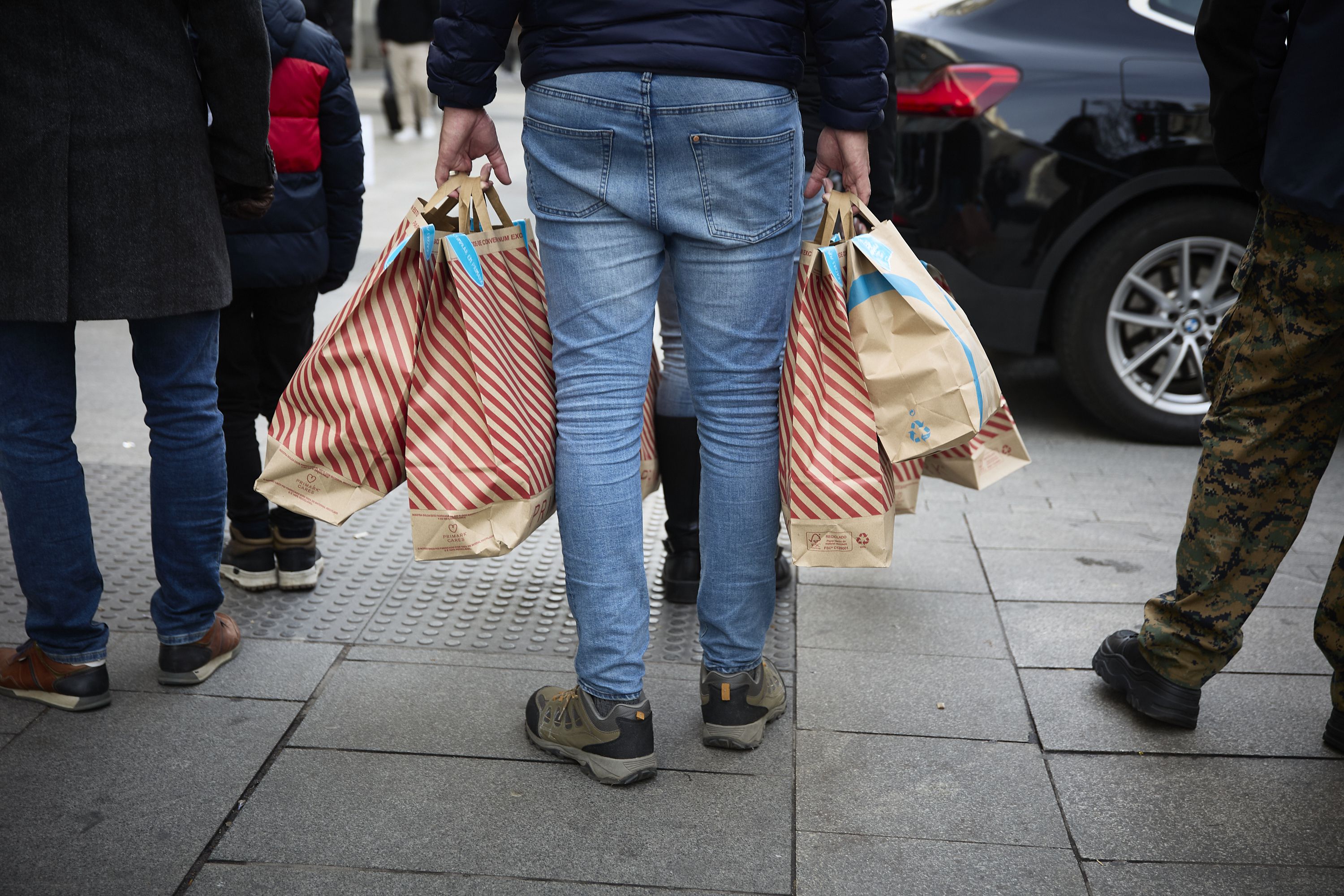 Una persona con bolsas en una calle comercial.