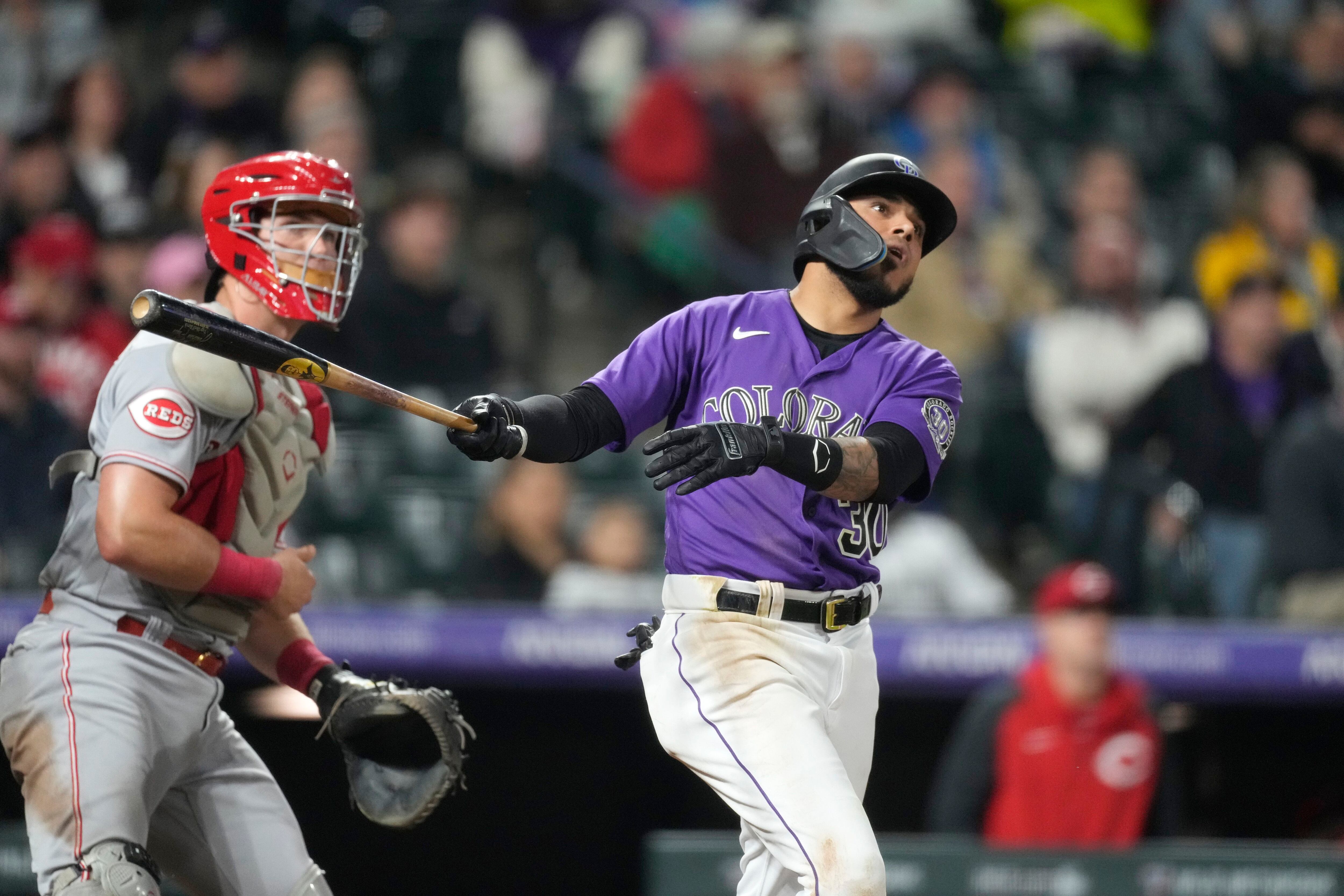 El venezolano Harold Castro, de los Rockies de Colorado, conecta un doble de dos anotaciones en la séptima entrada del partido contra los Rojos de Cincinnati en Denver, el lunes 15 de mayo de 2023. A la izquierda, el receptor de los Rojos, Tyler Stephenson. (AP Foto/David Zalubowski)