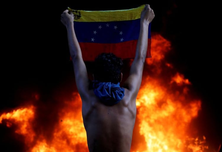 Imagen de archivo de un manifestante sosteniendo una bandera de Venezuela en medio de protestas contra Nicolás Maduro, en Caracas, Junio 12, 2017. REUTERS/Carlos Garcia Rawlins