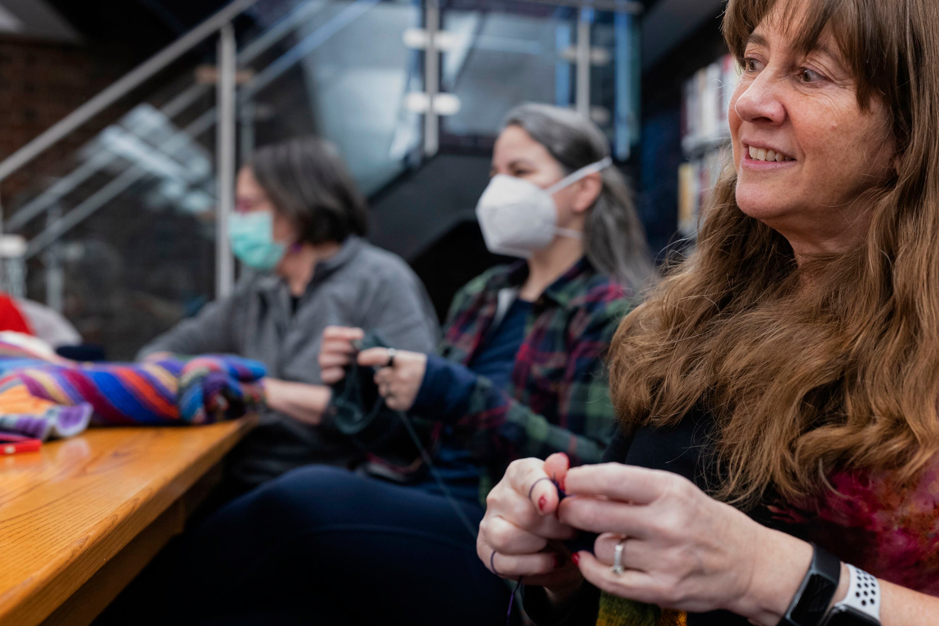 En esta imagen proporcionada por Edward Boches, Roz Switalski, a la derecha, teje una manta en un grupo de punto con otras voluntarias, el 8 de enero de 2023 en Brookline, Massachusetts. Las Mantas de Bienvenida se donarán a agencias que ayudan a inmigrantes llegados hace poco a Estados Unidos. (Edward Boches via AP)