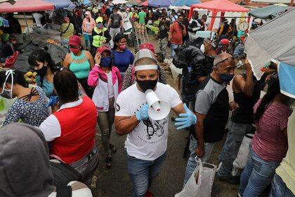 FOTO DE ARCHIVO-Walter Rivera, director del mercado mayorista Coche, anuncia con un megáfono las reglas para evitar el coronavirus (COVID-19) a locatarios y clientes en Caracas, Venezuela. 23 julio 2020. REUTERS/Manaure Quintero