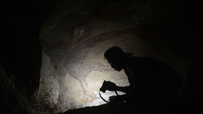 Esta imagen sin fecha muestra a un fotógrafo en la oscuridad de la cueva captando pruebas de la pintura rupestre más antigua conocida del mundo (Foto de Adhi Agus OKTAVIANA / UNIVERSIDAD GRIFFITH / AFP)