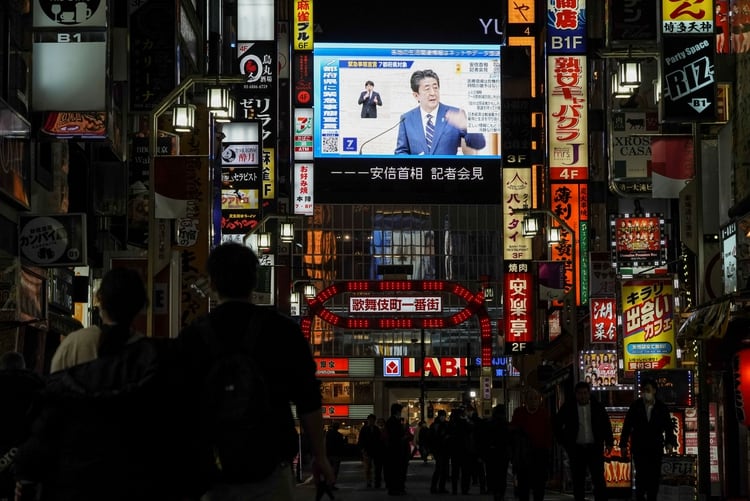 Una pantalla muestra al primer ministro japonés Shinzo Abe anunciar el estado de emergencia en el distrito Kabukicho de Tokyo (REUTERS/Naoki Ogura/archivo)