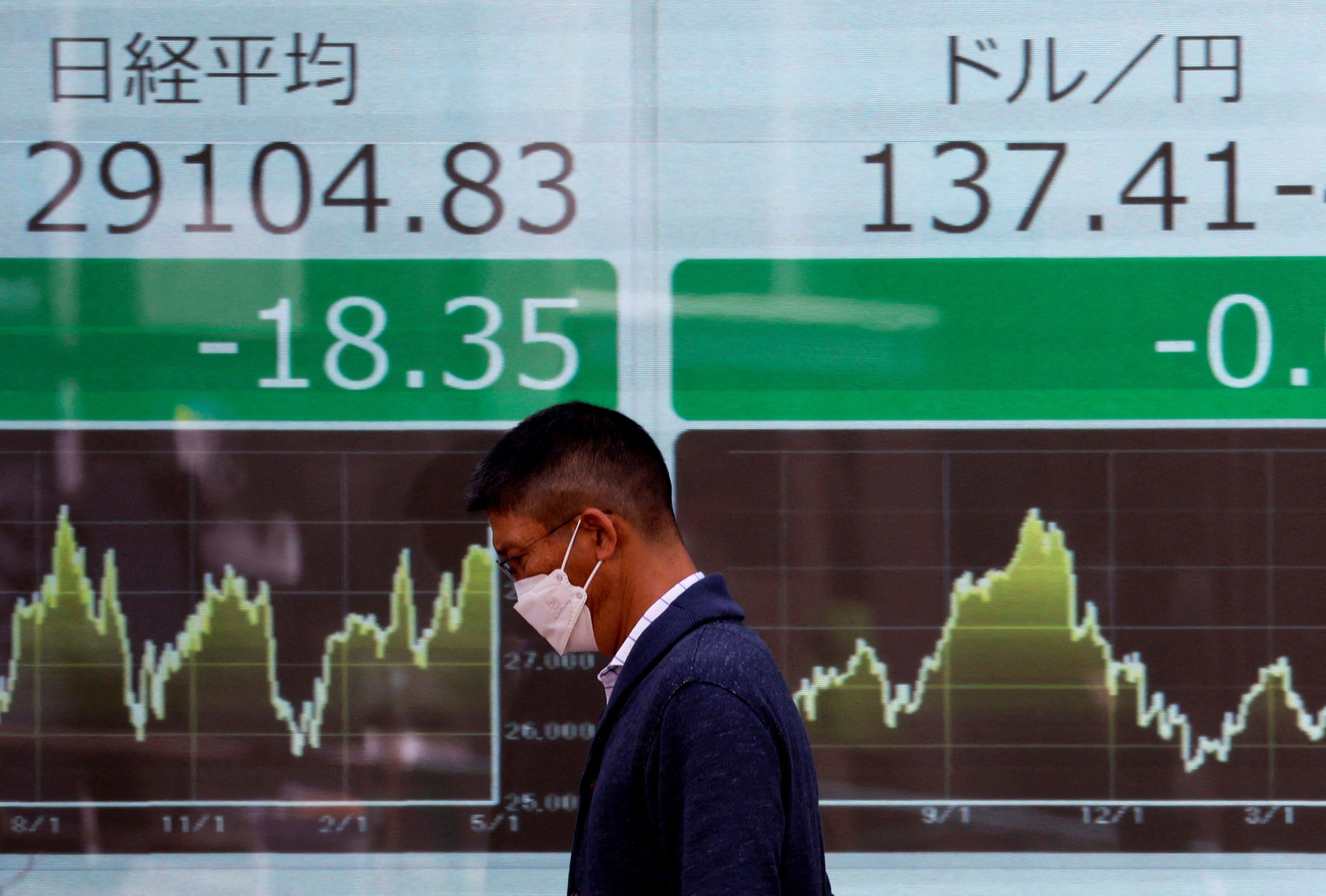Un hombre pasa junto a un monitor eléctrico que muestra el promedio de acciones Nikkei y el tipo de cambio del yen japonés frente al dólar estadounidense (REUTERS/Issei Kato/Fotografía de archivo)