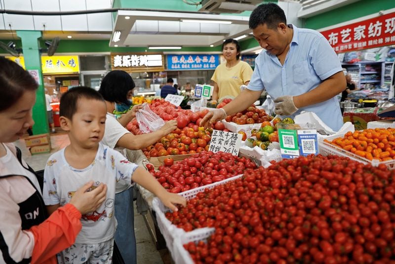 Clientes seleccionan tomates en un puesto dentro de un mercado matutino en Beijing, China. REUTERS/Tingshu Wang