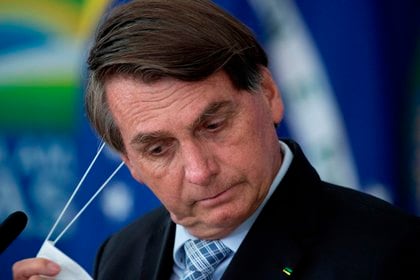 El presidente de Brasil, Jair Bolsonaro, reacciona mientras sanciona los proyectos de ley que amplían la capacidad de adquisición de vacunas por parte del Gobierno Federal, en el Palacio de Planalto, en Brasilia (Brasil). EFE/ Joédson Alves
