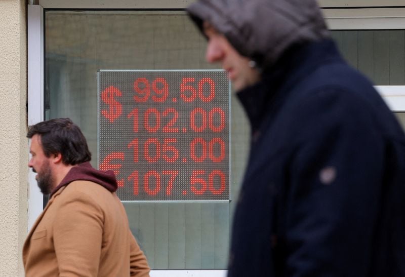 Peatones junto a un tablero electrónico que muestra los tipos de cambio del dólar estadounidense y el euro frente al rublo ruso en una calle de Moscú (REUTERS/Evgenia Novozhenina)