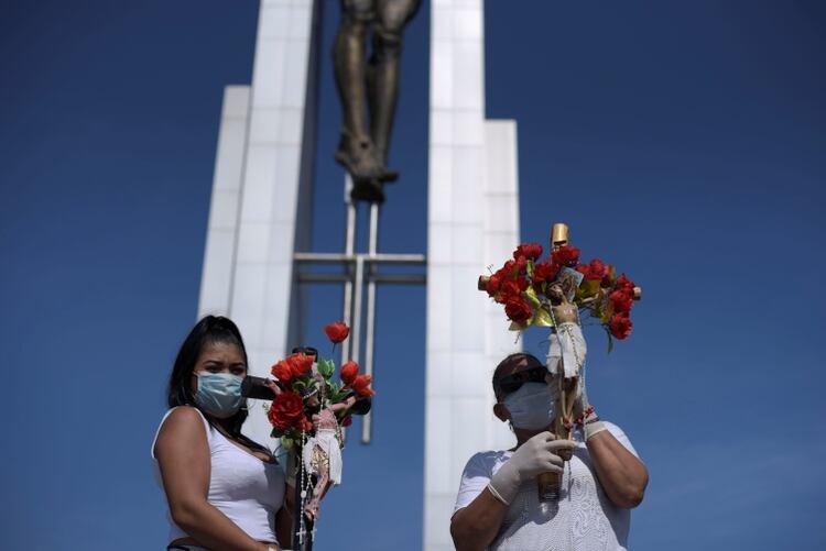 Mujeres con crucifijos y flores posan con mascarillas faciales durante las celebraciones de pascua en Guayaquil, Ecuador (REUTERS/Vicente Gaibor del Pino NO RESALES. NO ARCHIVES)