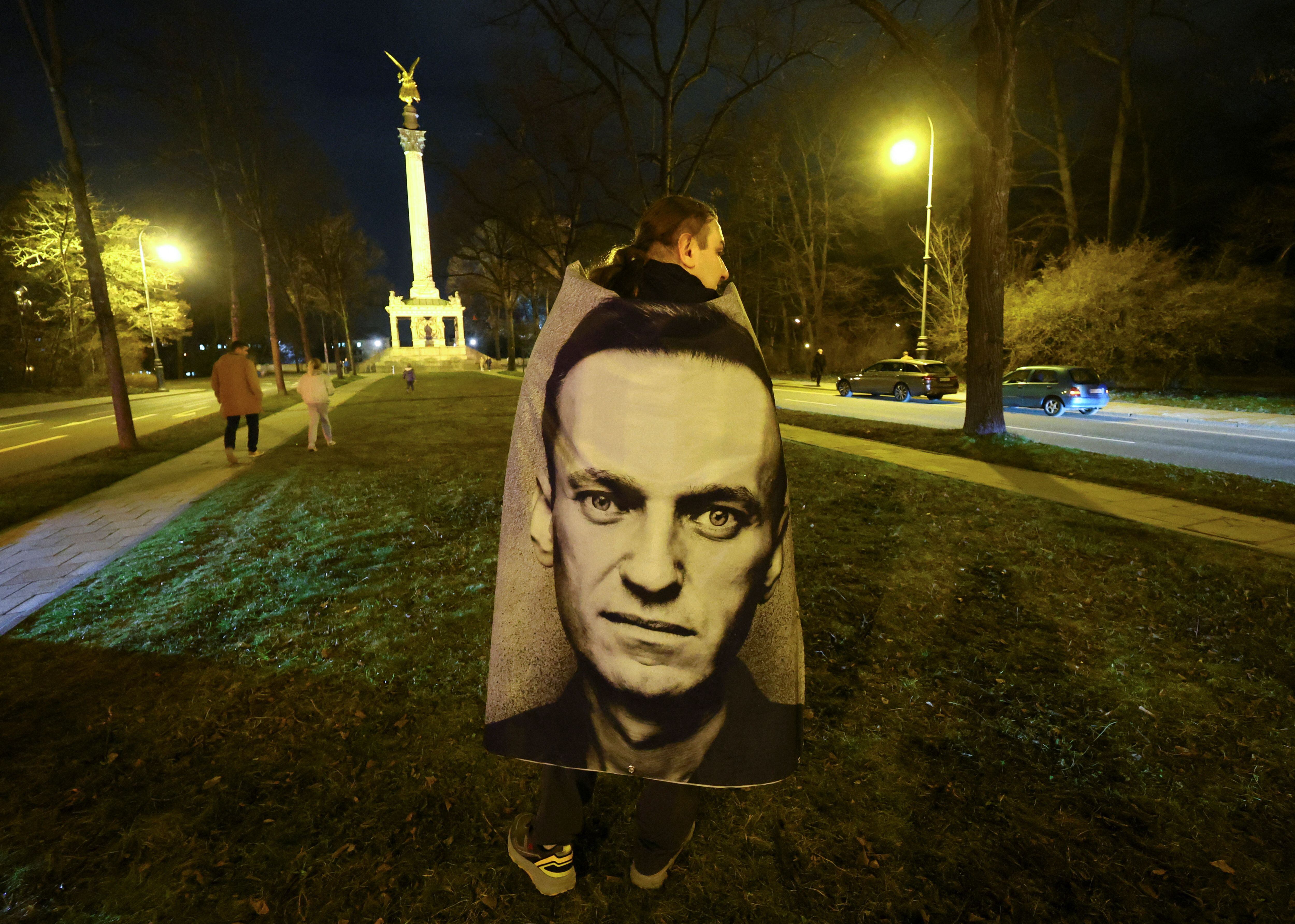 Una persona envuelta en una pancarta con la imagen del líder de la oposición rusa Alexei Navalny asiste a una vigilia en su memoria frente al consulado ruso en la plaza Europa, en Munich, Alemania, el 16 de febrero de 2024 (REUTERS/Wolfgang Rattay)