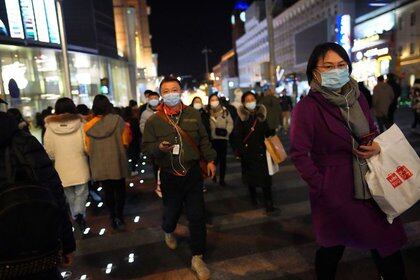 La gente camina en una calle comercial en Nochebuena mientras la epidemia mundial de coronavirus (COVID-19) continúa en Beijing, China.  24 de diciembre de 2020. REUTERS / Tingshu Wang