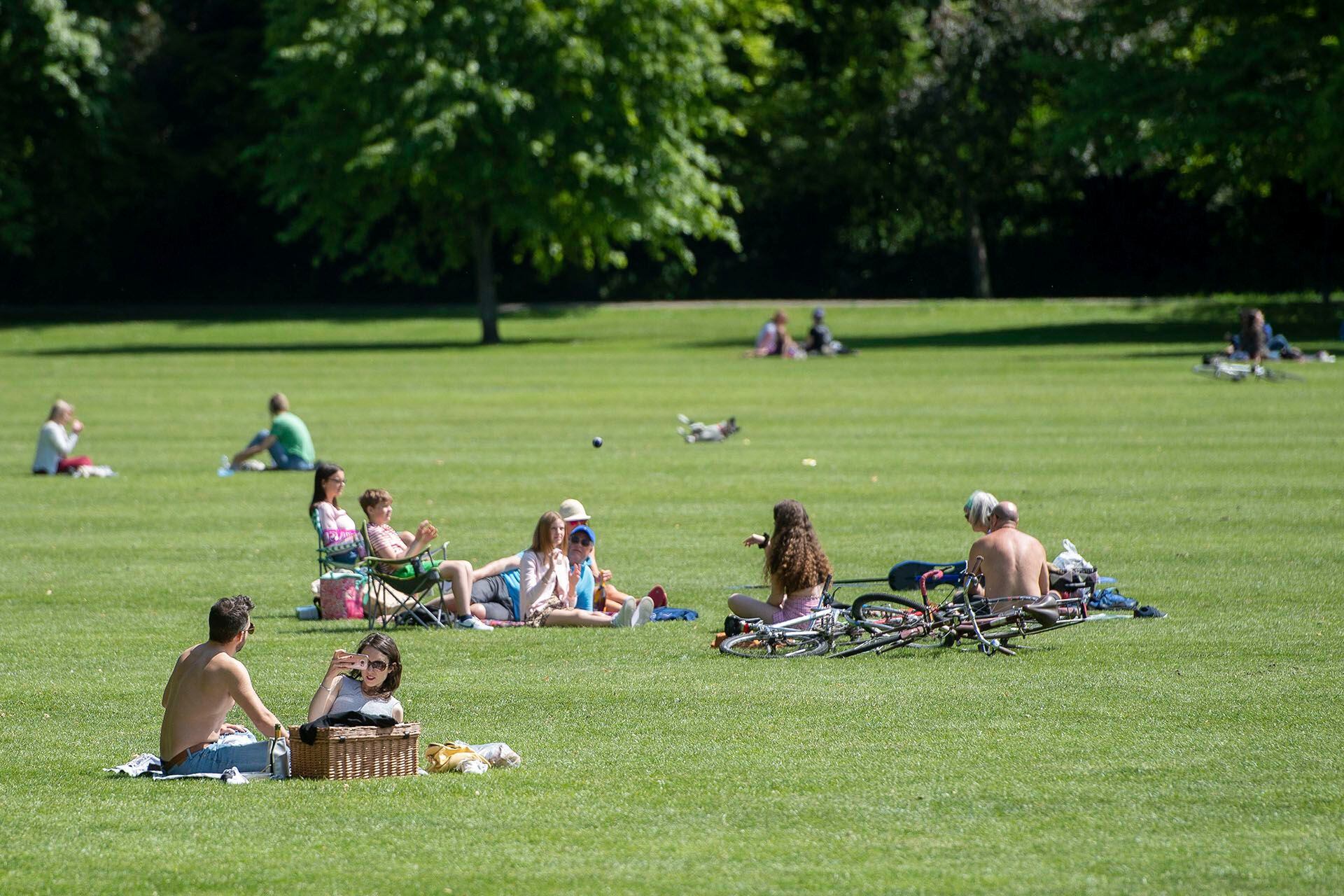 Distancia social entre quienes disfrutan de una soleada tarde en Jesus Green en Cambridge, Inglaterra. 