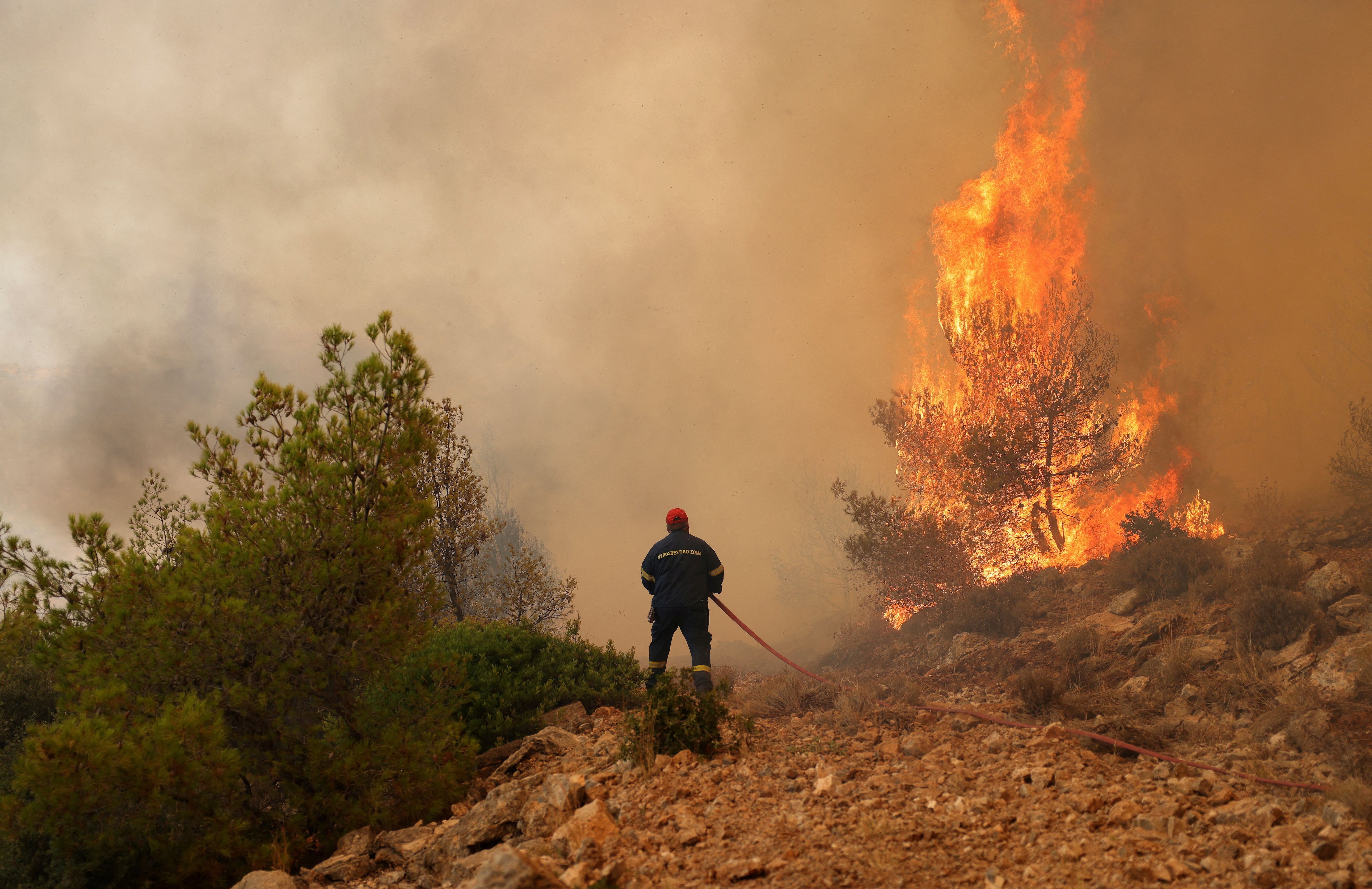Un bombero intenta extinguir un incendio forestal que arde cerca del pueblo de Kandyli, cerca de Atenas, Grecia, 19 de julio de 2023. REUTERS/Stelios Misinas 