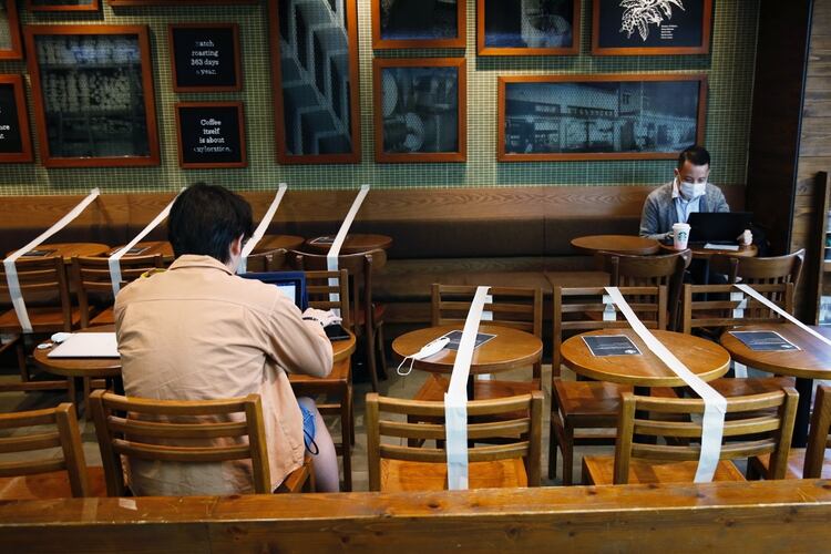 Las mesas y las sillas están señalizadas para mantener el distanciamiento social en una cafetería Starbucks en Hong Kong (Reuters)
