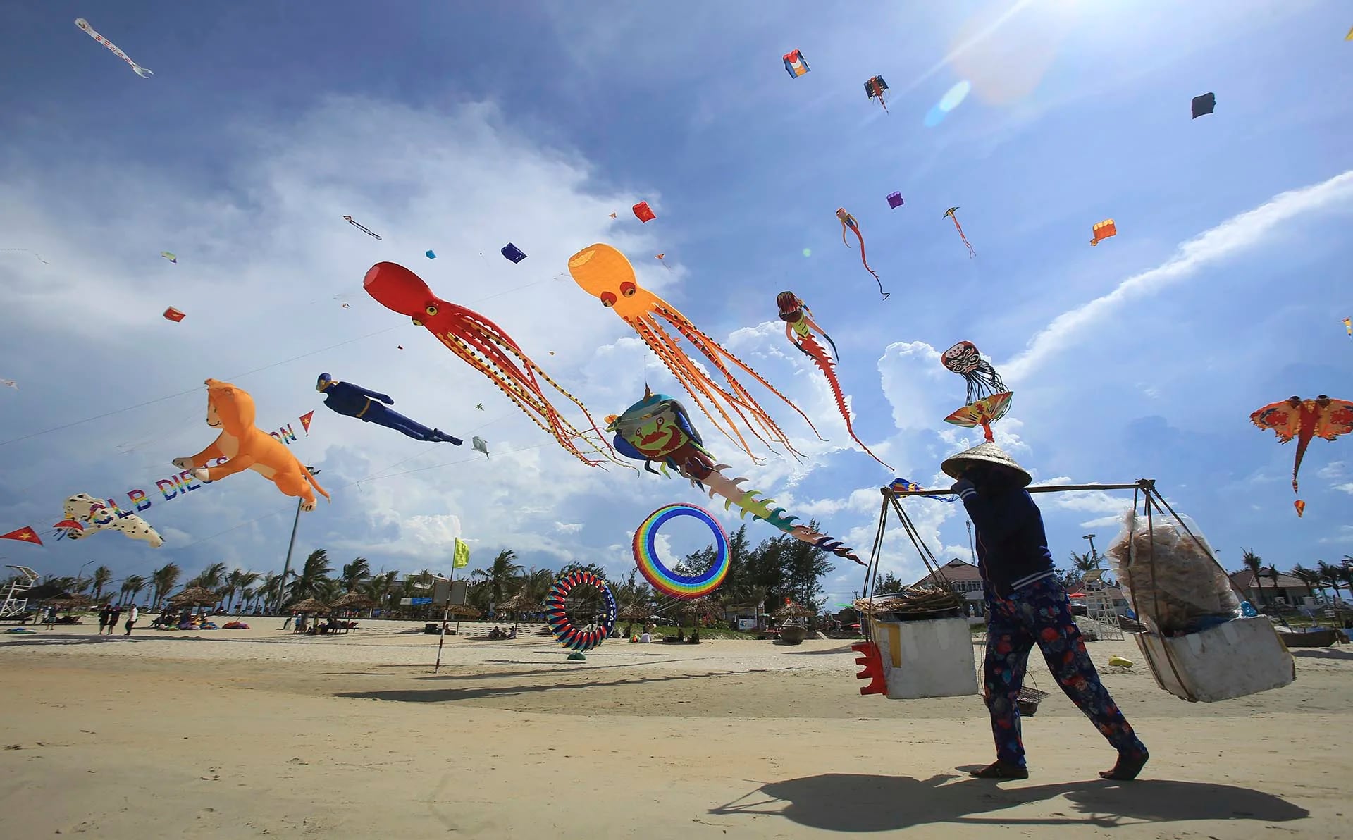 Durante el Festival Internacional de cometas, en la playa de Tam Thanh, ubicada en la provincia de Quang Nam, en Vietnam, un vendedor de comida camina debajo de ellas (AP)