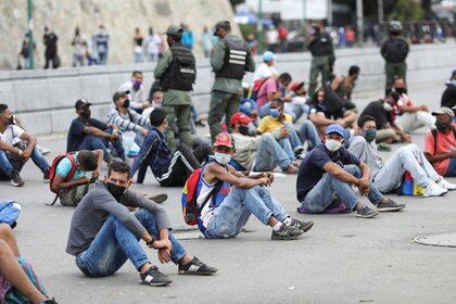 Personas son colocadas en medio de la calle por fuerzas de seguridad en el barrio de Petare como castigo por no respetar las medidas de distanciamiento social, en Caracas (REUTERS/Manaure Quintero)