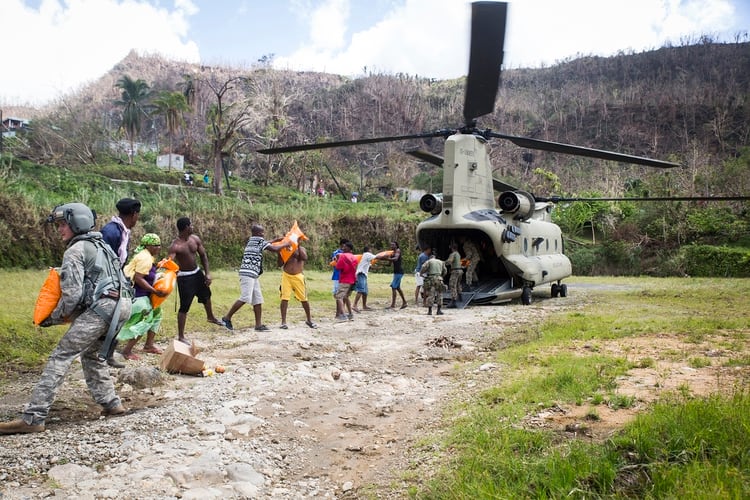 El sargento del ejército de EE. UU. Delton Reynolds, izquierda, ingeniero de vuelo con la Fuerza de Tarea Conjunta - Islas de Sotavento, se une a una cadena con residentes locales y miembros de la Fuerza de Defensa de Jamaica para descargar suministros de socorro de un helicóptero Chinook CH-47 en Wotten Waven, Dominica, el 3 de octubre, 2017. (Foto del Cuerpo de Marines de los EE. UU/ Ian Leones)