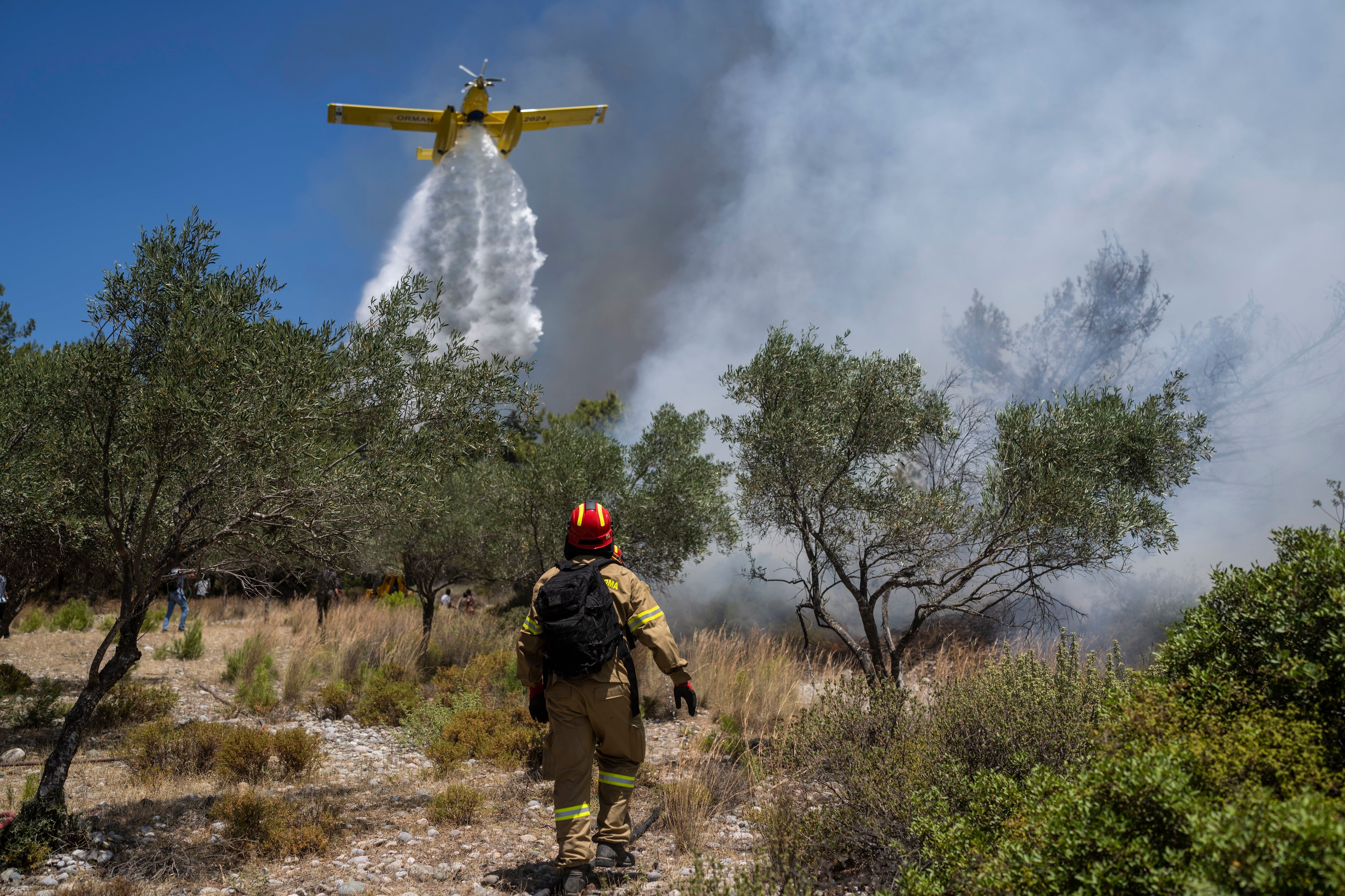 Un avión arroja agua sobre un incendio forestal en la aldea de Vati, en la isla de Rodas, en el mar Egeo, al sureste de Grecia, el martes 25 de julio de 2023. (Foto AP/Petros Giannakouris)