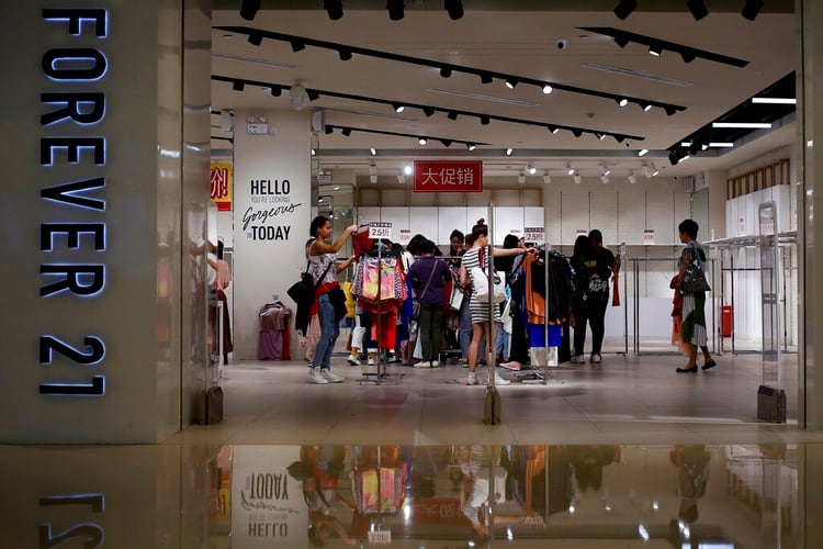 En esta imagen de archivo del martes 7 de mayo de 2019, mujeres mirando ropa en una tienda de la minorista estadounidense Forever 21, que ofrecía descuentos por liquidación en un centro comercial tras anunciar su salida del mercado chino, en Beijing. (AP Foto/Andy Wong, Archivo)