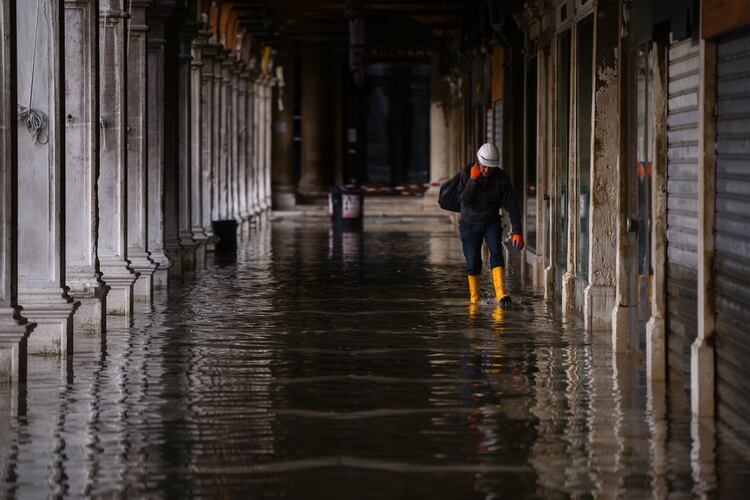 Un hombre con botas camina en Venecia. (AFP)