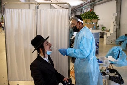 Un trabajador de la salud realiza un hisopado para detectar el coronavirus a un joven ortodoxo en el Aeropuerto Internacional Ben Gurion en Lod, cerca de Tel Aviv, Israel el 13 de abril de 2021 REUTERS / Ronen Zvulun / Foto de archivo