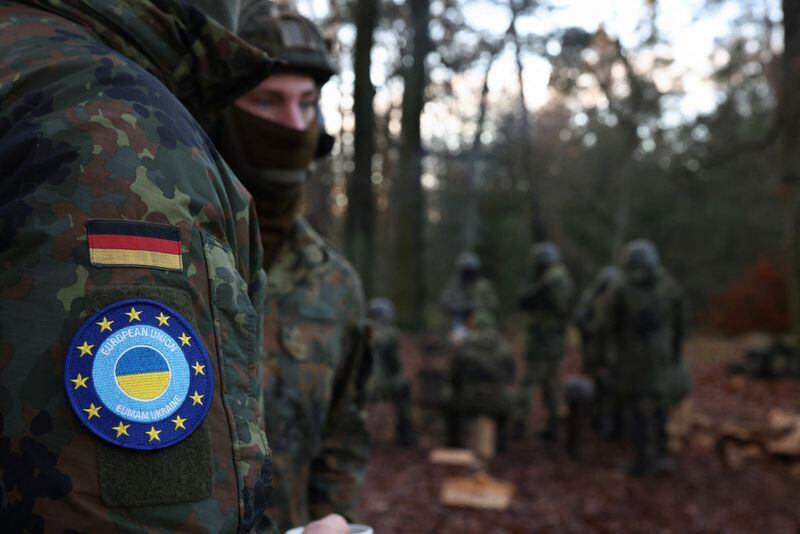 El logotipo de la Misión de Asistencia Militar de la UE en apoyo de Ucrania y la bandera nacional de Alemania en el uniforme de un soldado durante un entrenamiento (REUTERS/Liesa Johannssen)