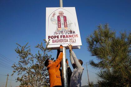 Los voluntarios cristianos decoran las calles con las fotos del Papa Francisco antes de su visita planificada a Irak (Reuters)