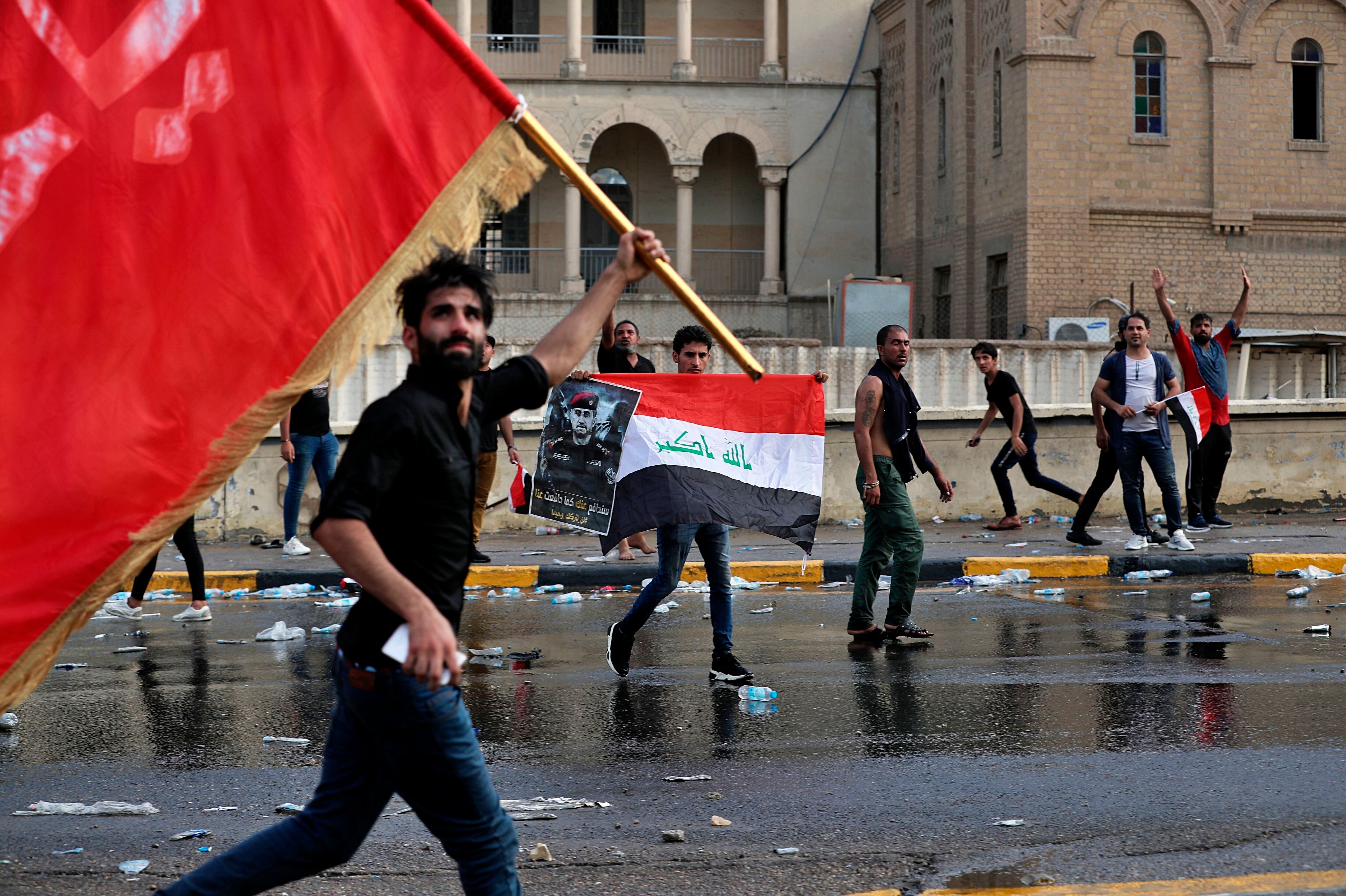 Manifestantes ondeando banderas y sosteniendo un cartel con la imagen del teniente general Abdul-Wahab al-Saadi, durante una protesta en la Plaza Tahrir, en el centro de Bagdad, Irak, el martes 1 de octubre de 2019. (AP Foto/Khalid Mohammed)