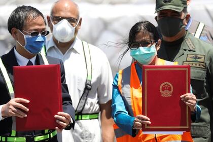 La vicepresidenta del régimen venezolano, Delcy Rodríguez, con el embajador chino en Caracas, Li Baorong, recibieron el cargamento de artículos sanitarios enviados por Beijing (REUTERS/Manaure Quintero)