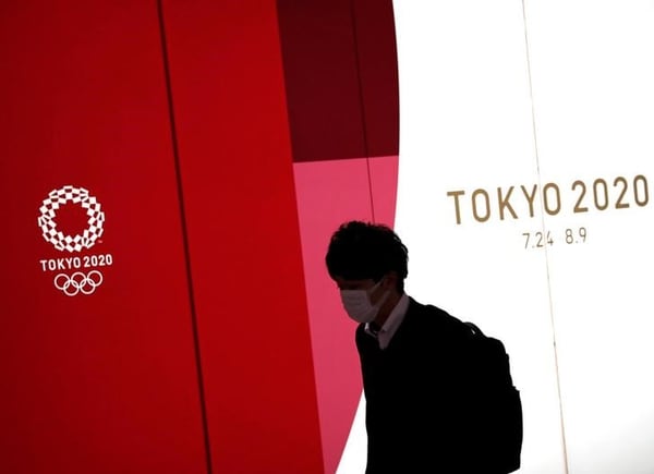 Un hombre que utiliza una mascarilla pasa delante de un tablero decorado con logos de los Juegos Olímpicos de Tokio 2020, en Tokio, Japón REUTERS/Issei Kato