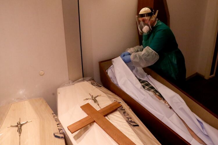 Un operario cierra un bolsa con el cuerpo de un fallecido por coronavirus en una morgue en Bruselas, Bélgica (Reuters)