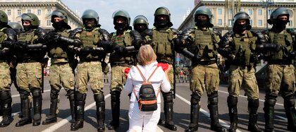 A woman kneels in front of a riot police line as they block Belarusian opposition supporters rally in the center of Minsk, Belarus, Sunday, Aug. 30, 2020. Opposition supporters whose protests have convulsed the country for two weeks aim to hold a march in the capital of Belarus. (AP Photo)