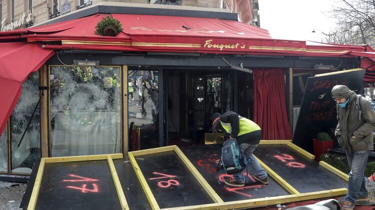 Un manifestante pinta con grafiti el frente del restaurante (Photo by Thomas SAMSON / AFP)