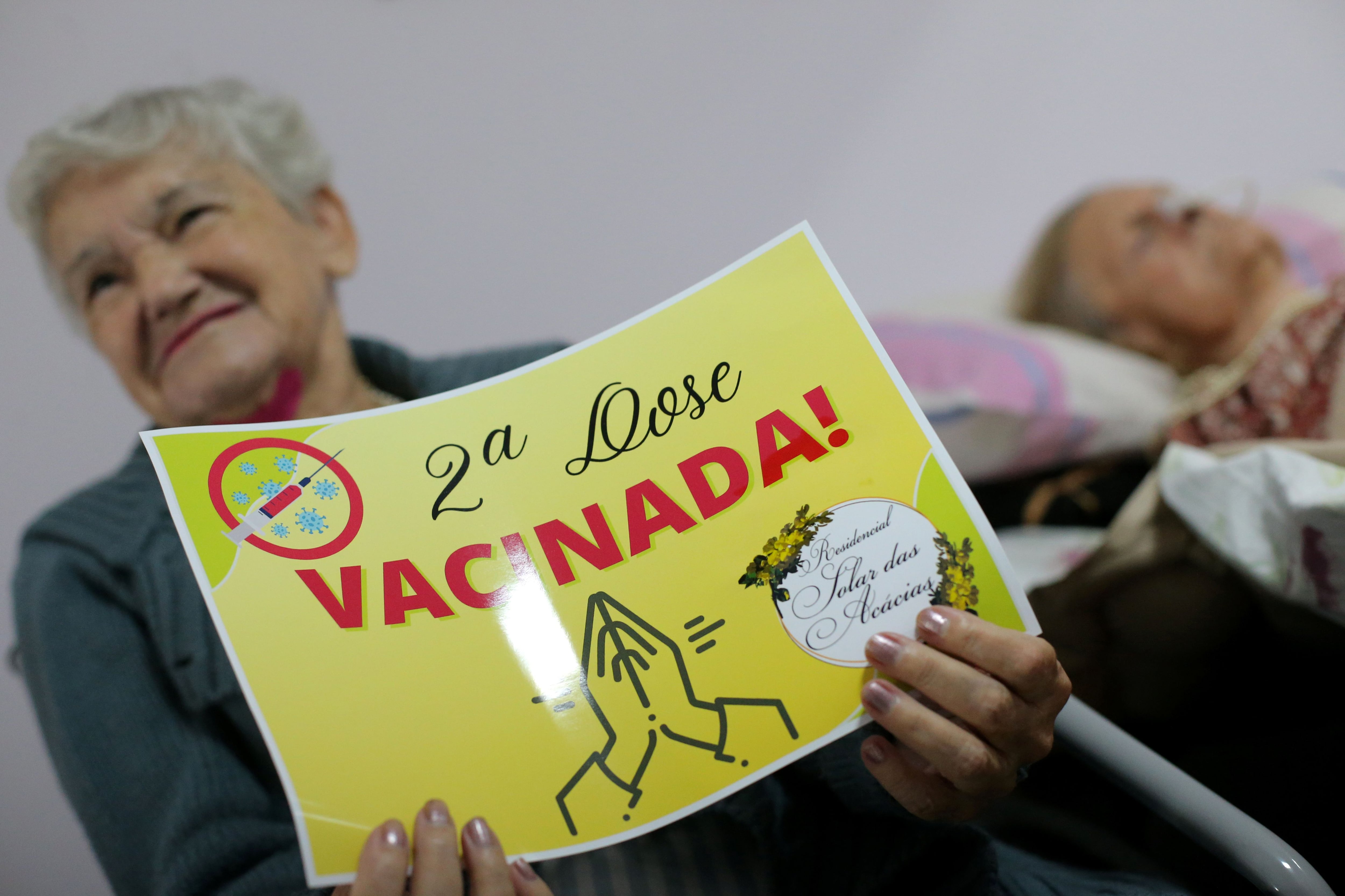 Una mujer ostenta un cartel después de recibir la segunda dosis de la vacuna en un geriátrico de San Pablo, Brasil - REUTERS/Carla Carniel