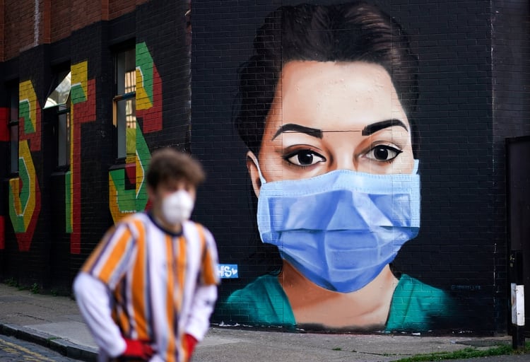 Un hombre con máscara protectora camina delante de un mural de una enfermera en Londres, Reino Unido. REUTERS/Henry Nicholls TPX IMAGES OF THE DAY