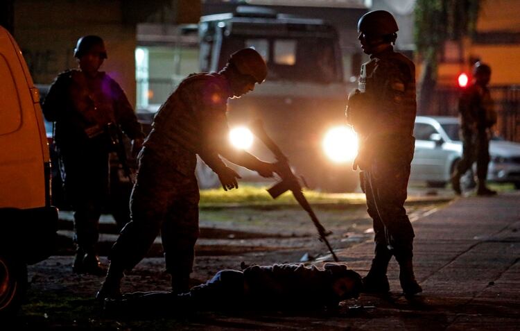 Un militar chileno apunta con su fusil a un civil que está en el suelo. (telam)