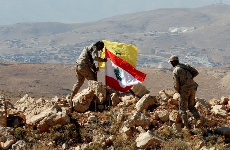 Terroristas de Hezbollah colocan una bandera de su grupo armado y del Líbano en la frontera entre su país y Siria (Reuters)