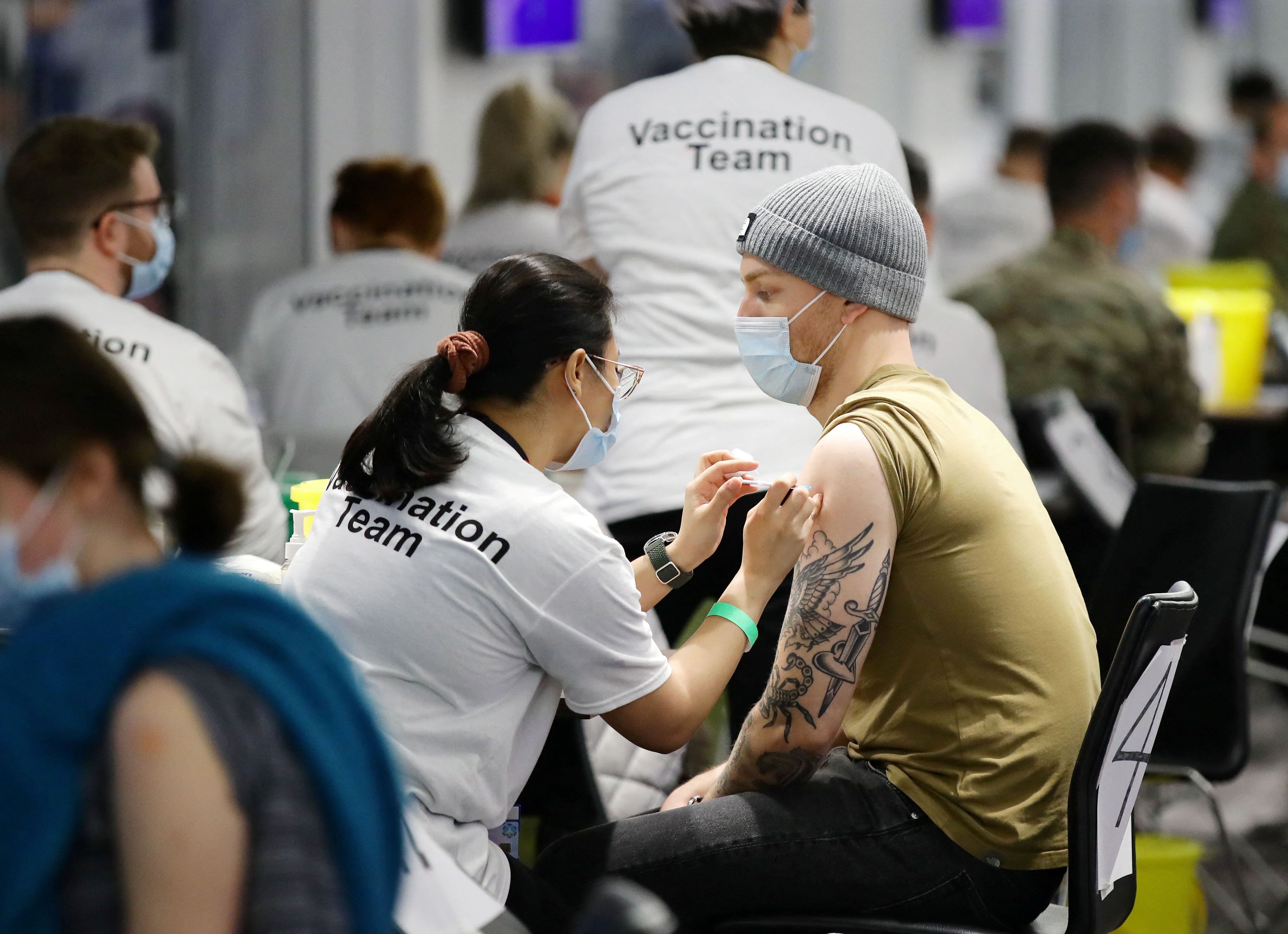 Las personas reciben una dosis de refuerzo dentro de un centro de vacunación instalado en el campo de fútbol del Chelsea, Stamford Bridge en Londres, Gran Bretaña, 18 de diciembre de 2021. (REUTERS/David Klein)