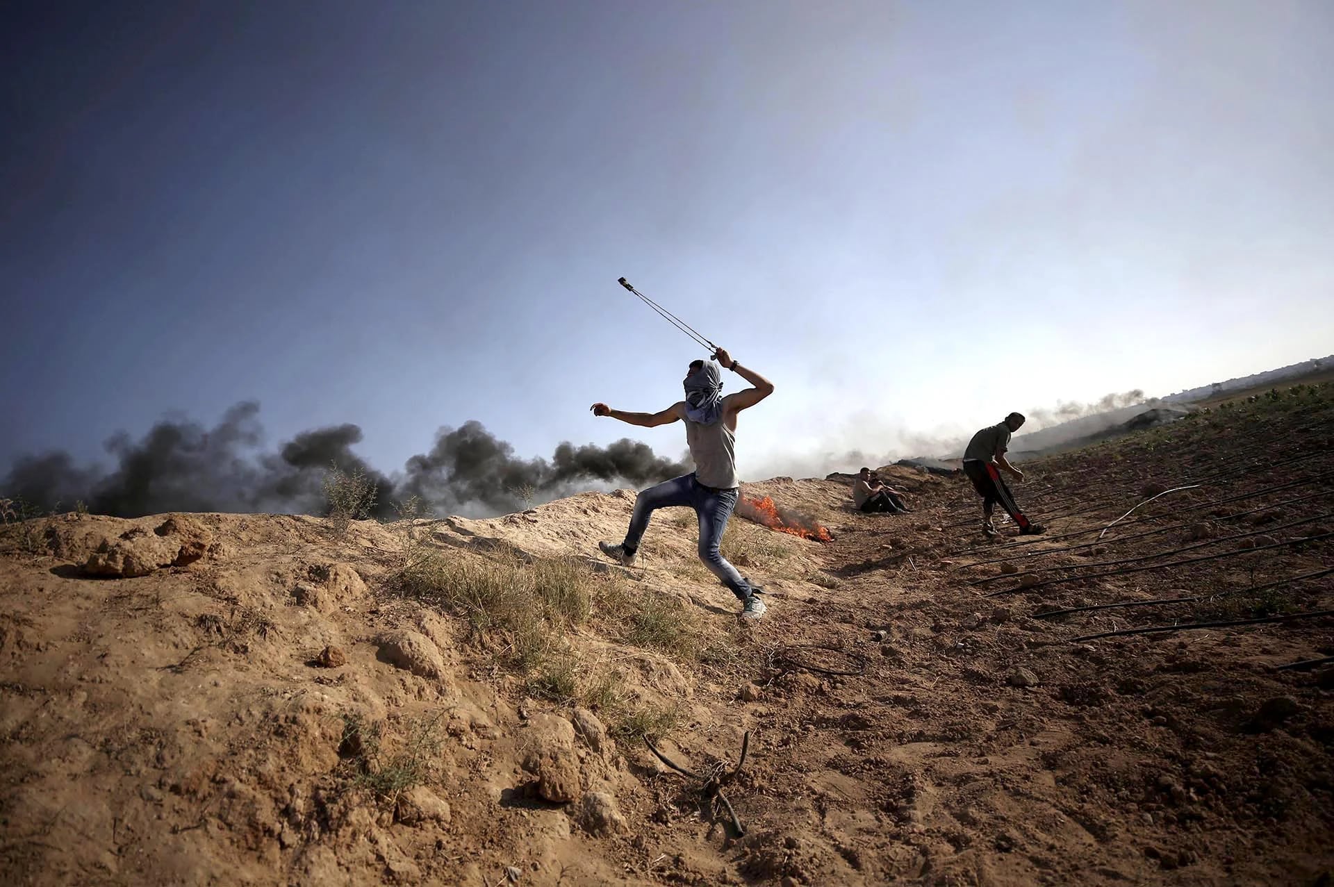 Un palestino lanza una piedra durante los enfrentamientos entre manifestantes palestinos y soldados israelíes junto a la frontera con Israel al norte de la franja de Gaza