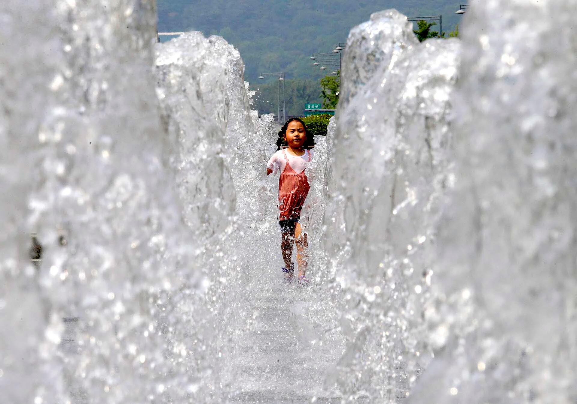Una niña corre a través de una fuente de agua pública para refrescarse en Seúl, Corea del Sur