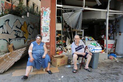 Una pareja que sufrió algunas heridas se sienta frente a su comercio, con daños materiales por la explosión (Reuters)