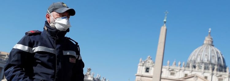 Un policía con mascarilla vigila una Plaza de San Pedro vacía desde Roma, Italia. (REUTERS/Guglielmo Mangiapane)