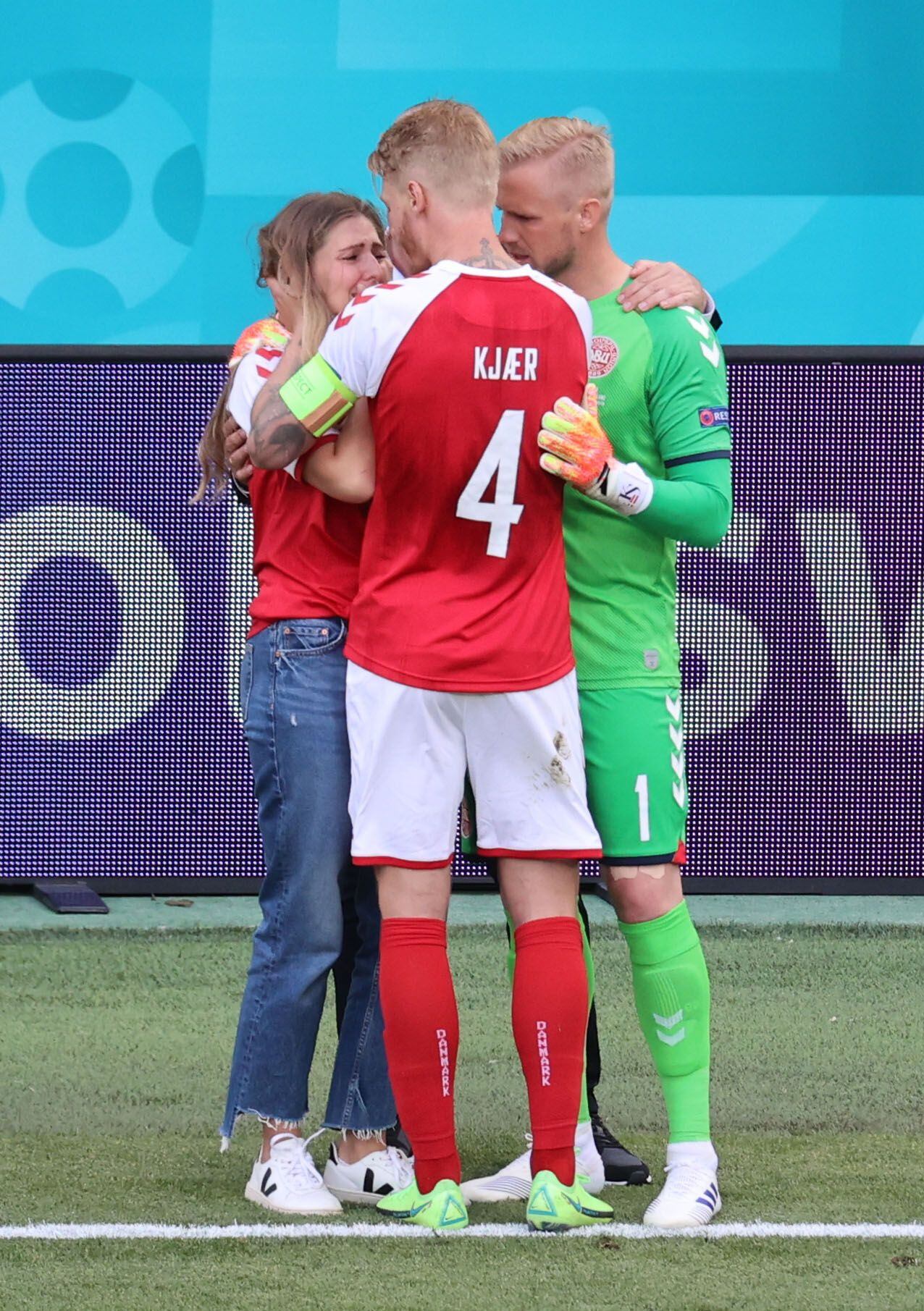 Sabrina Kvist Jensen, esposa de Eriksen, abrazada por Simon Kjaer y Kasper Schmeichel en el campo de juego (Foto: REUTERS)